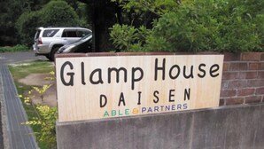 Un senyal de fusta de Glamp House Daisen amb la inscripció 'ABLE & PARTNERS'.