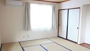 Una habitació amb sòl de tatami, una porta corredissa i una finestra amb cortines.