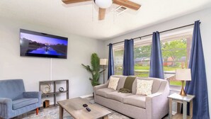 A living room with a television, sofa, coffee table, and a plant. - Pool, Fenced Yard, & Patio! Ventura Vista Retreat (Columbus)