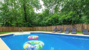 A swimming pool with two inflatable rings, a wooden fence, and six lounge chairs. - Pool, Fenced Yard, & Patio! Ventura Vista Retreat (Columbus)