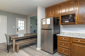 Una cocina con armarios de madera, un refrigerador de acero inoxidable, un microondas y una mesa de comedor con sillas.