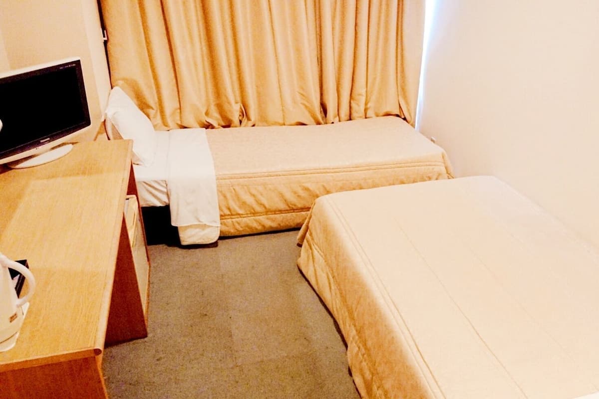 Una camera d'albergo con un letto, una scrivania, una sedia e una televisione.