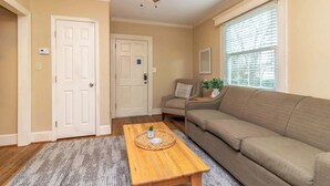 Ein Wohnzimmer mit Couch in Beige, Holztisch und Deckenventilator.