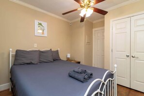 A bedroom with a bed, a ceiling fan, a door, and a wall-mounted light switch. - Pool! Near Downtown&Parks- The Cozy Guest Cottage (Columbus)