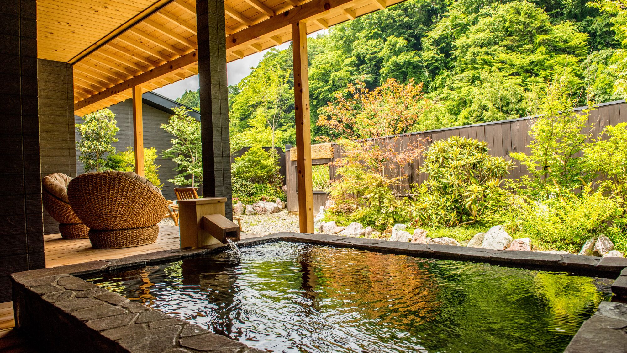 A wooden deck with a hot tub, a chair, and a small table.
