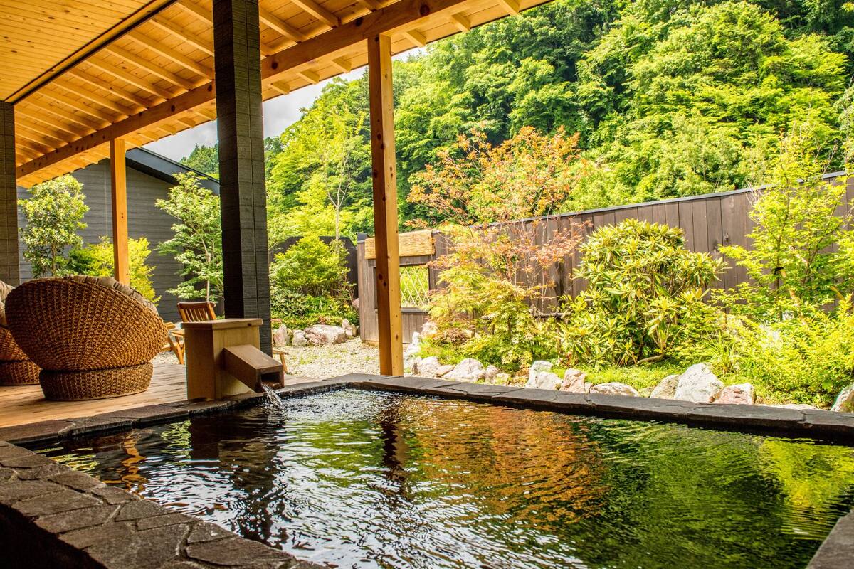 A wooden deck with a hot tub, a chair, and a small table.