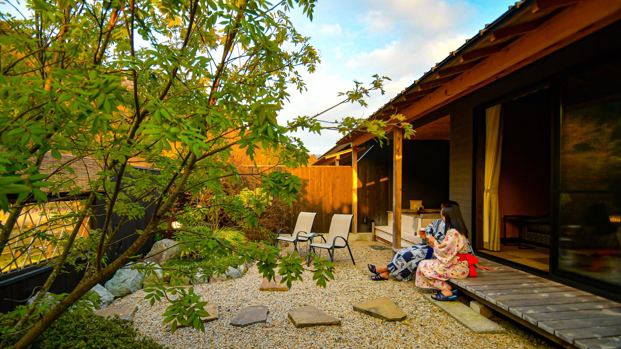 A patio area with chairs, a wooden deck, and a building with a large glass door.
