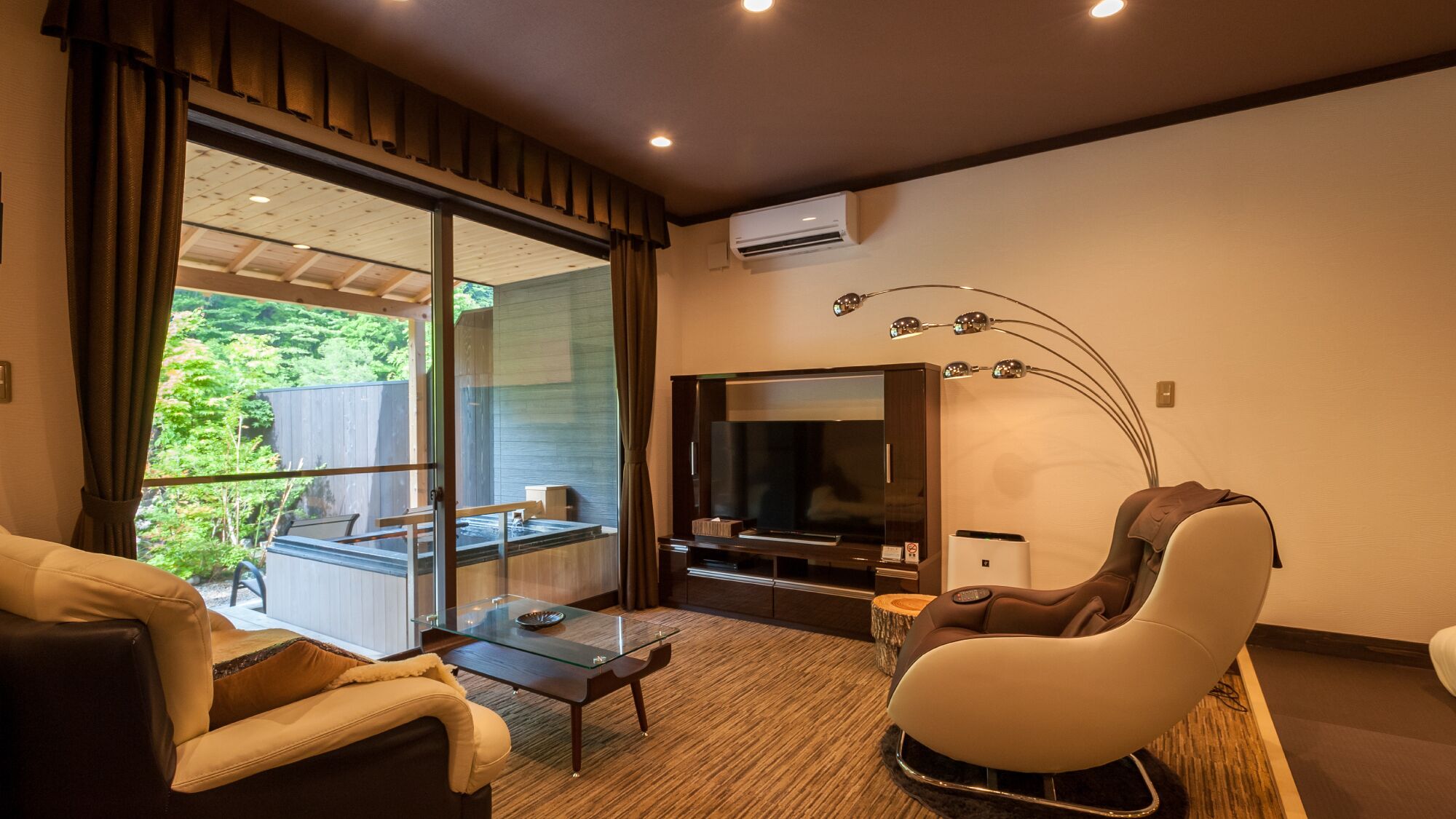A modern living room with a glass table, sofa, and a massage chair.