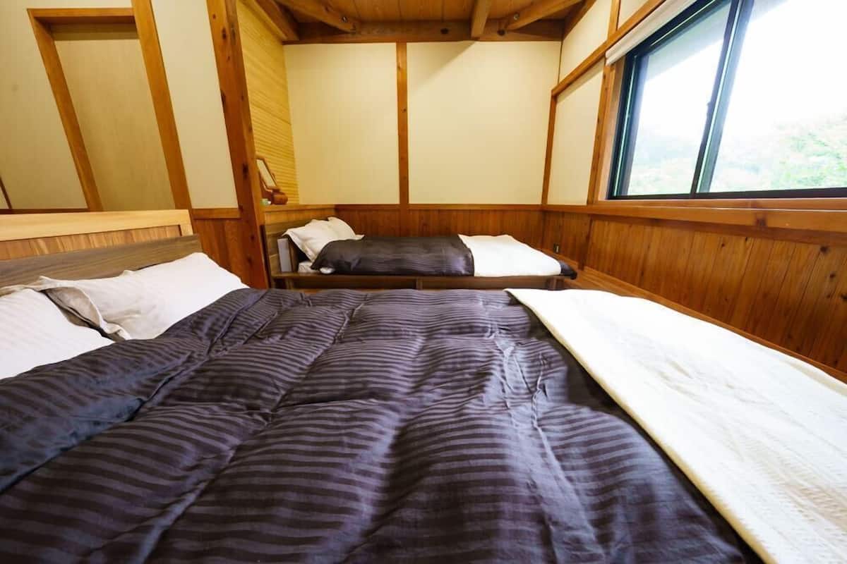 A room with a bed, a window, and wooden paneling.