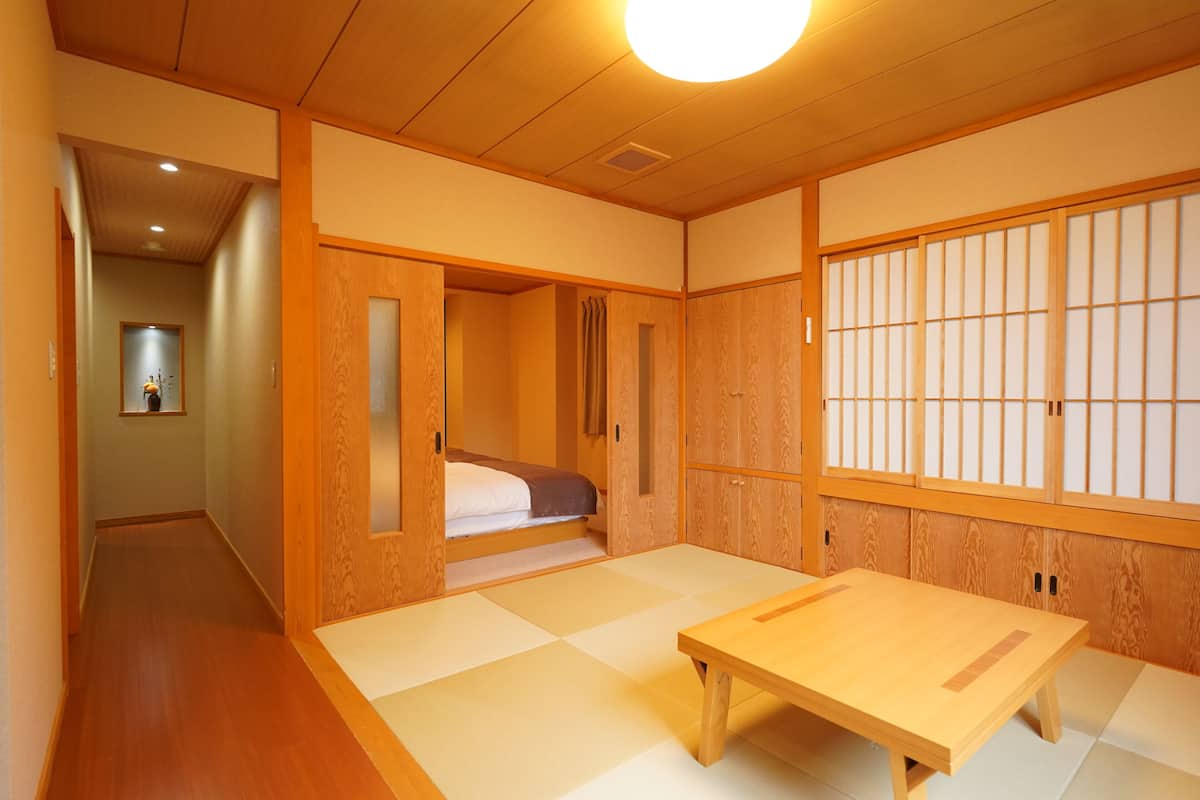 Une pièce de style japonais traditionnel, avec un sol recouvert de tatamis, une table en bois et des portes coulissantes.