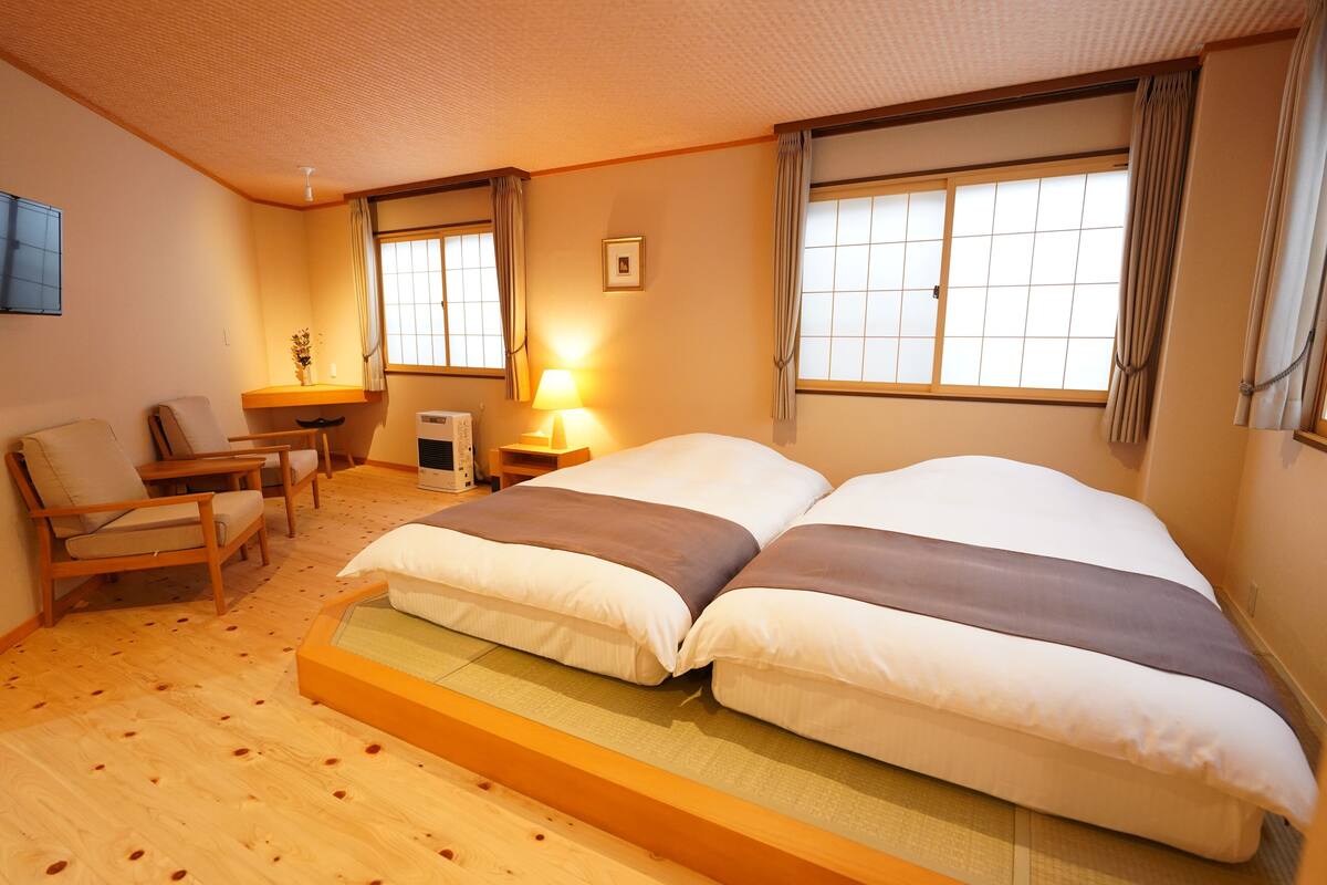 Une chambre d’hôtel avec un lit, deux chaises, un bureau, une lampe et une fenêtre.