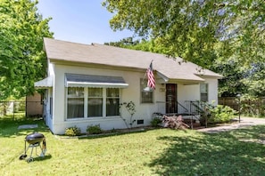 Een gelijkvloers huis met een veranda, een kleine voortuin en een Amerikaanse vlag.
