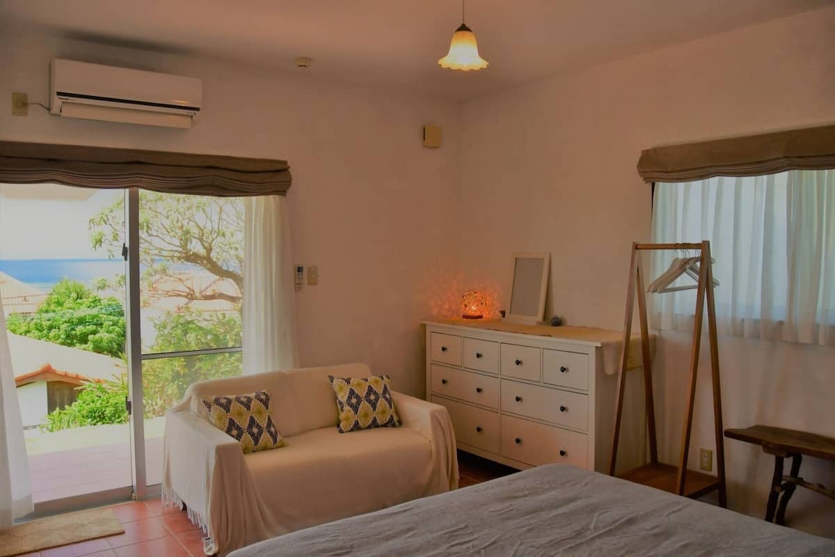 Ein Schlafzimmer mit Bett, Schminktisch, Hängesessel und Blick ins Freie.
