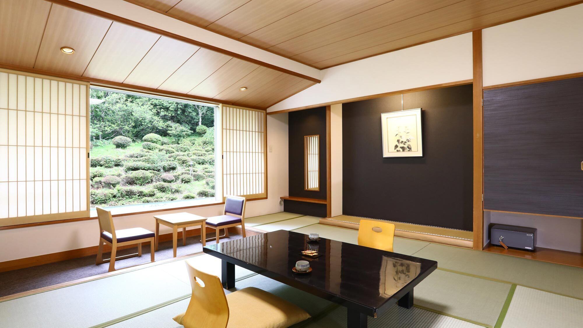 Une pièce de style japonais traditionnel, avec un sol recouvert de tatamis, une table basse, des chaises et une vue sur un jardin.