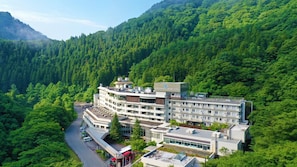 Un hôtel à plusieurs étages, doté d’un design moderne, et entouré d’une forêt dense.