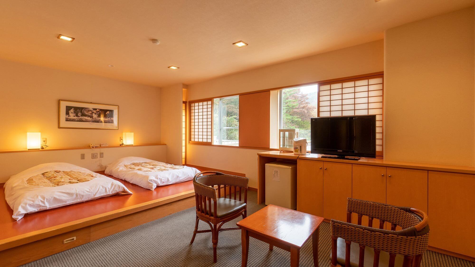 A hotel room with two beds, a television, a small table, and chairs.