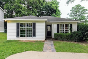 A single-story house with a front door, a small porch, and a stone pathway leading to the entrance. - Near Shops, Dining & Airport- The Hilltop Bungalow (Columbus)