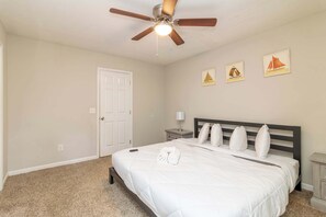Une chambre d’hôtel avec un lit, un ventilateur de plafond, une porte et des œuvres d’art murales.