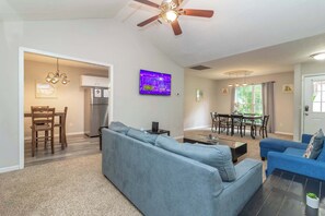 A modern living room with a sofa, a coffee table, and a TV mounted on the wall. - Near Shops, Dining & Airport- The Hilltop Bungalow (Columbus)