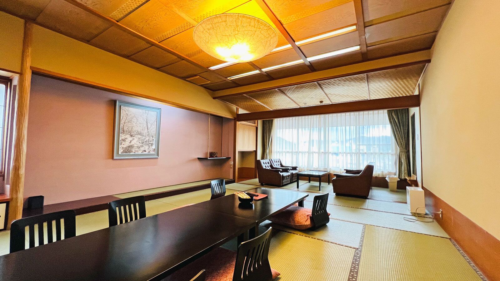 A traditional Japanese-style room with tatami flooring, a low table, and seating arrangements.