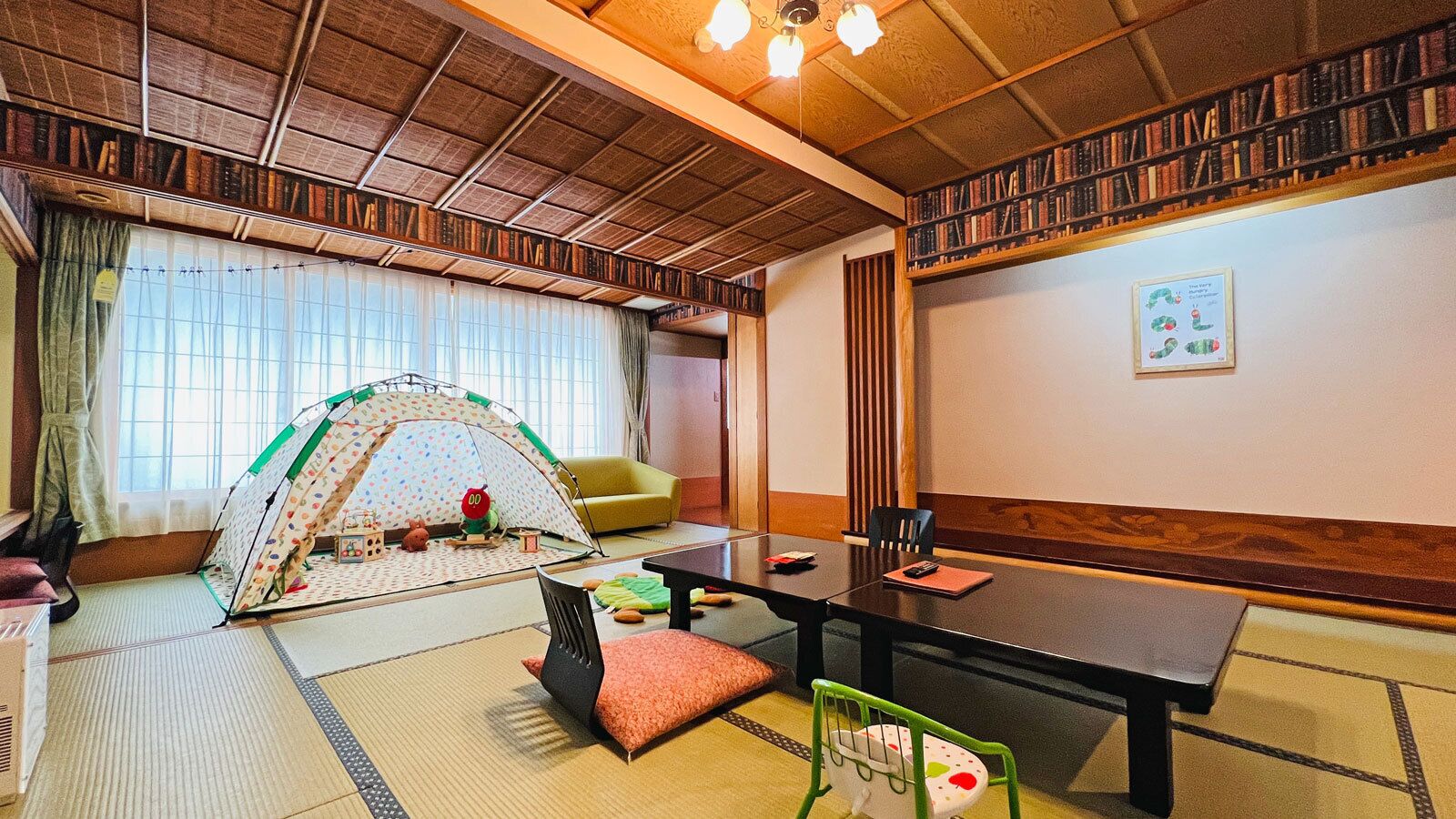 A traditional Japanese room with tatami flooring, a low table, a sofa, and a children's tent.