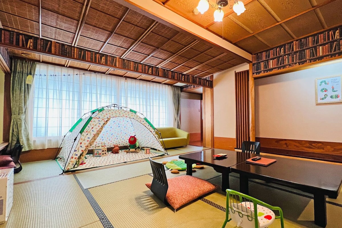 Une pièce de style japonais traditionnel, avec un sol recouvert de tatamis, une table basse, un canapé et une tente pour enfants.