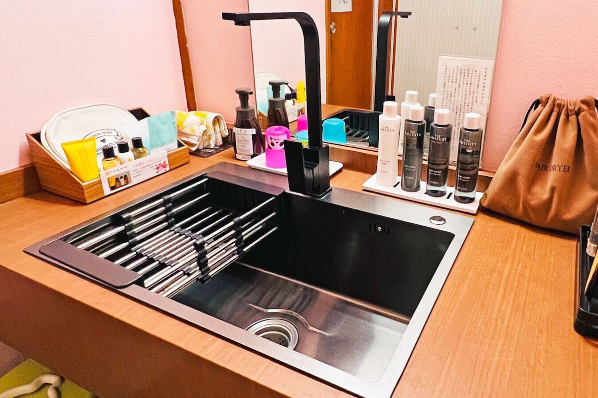 Une salle de bain moderne avec un lavabo en acier inoxydable, un miroir et divers produits de toilette disposés sur le comptoir.