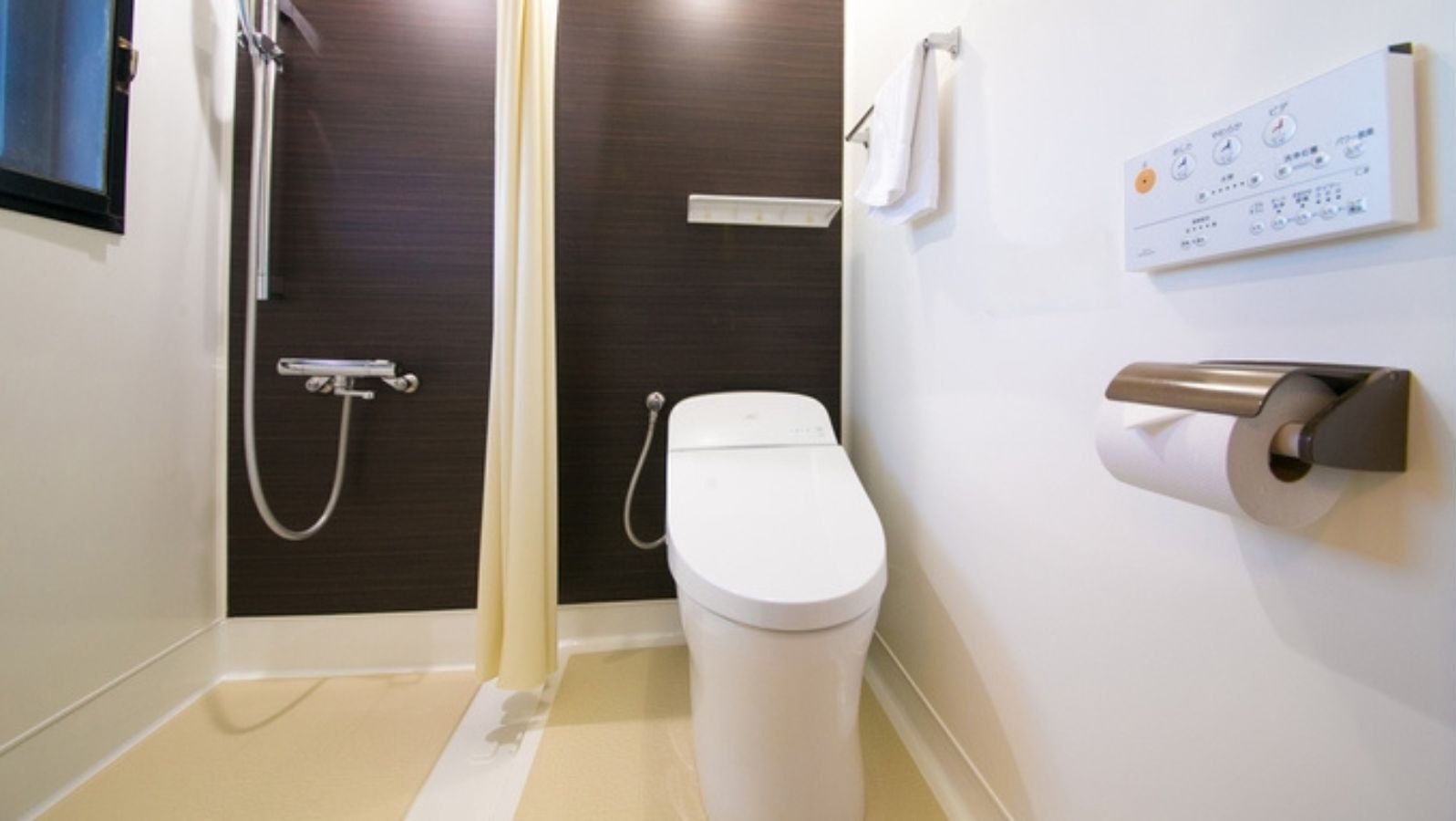 Un baño con inodoro, ducha y panel de control en la pared.