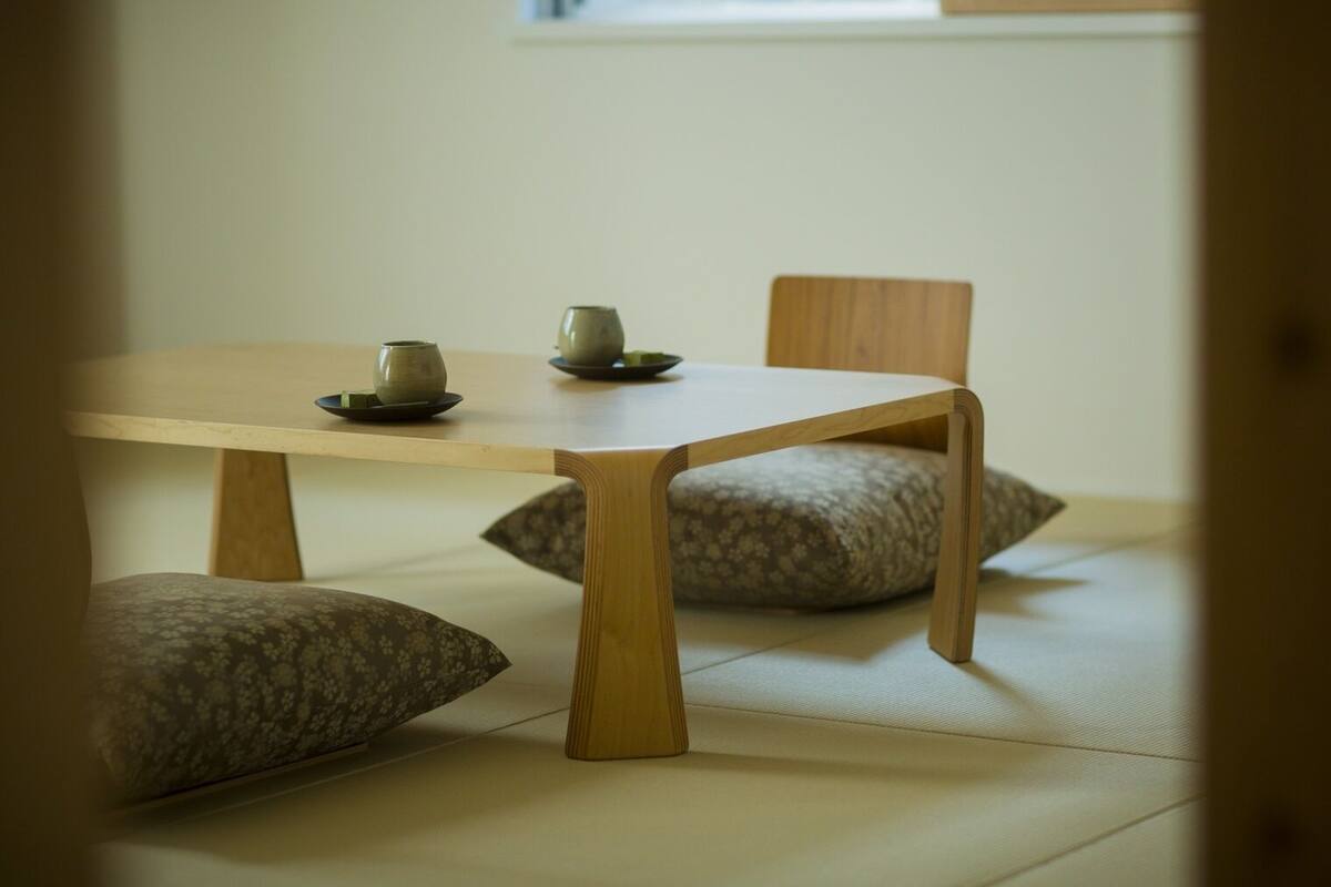 Una habitación tradicional japonesa con esteras de tatami, una mesa de madera baja, dos cojines y un pequeño juego de té.