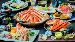 A variety of seafood dishes, including crab legs, sashimi, and other seafood preparations, arranged on a table.