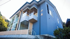 A modern building with large windows, a balcony, and a blue exterior.