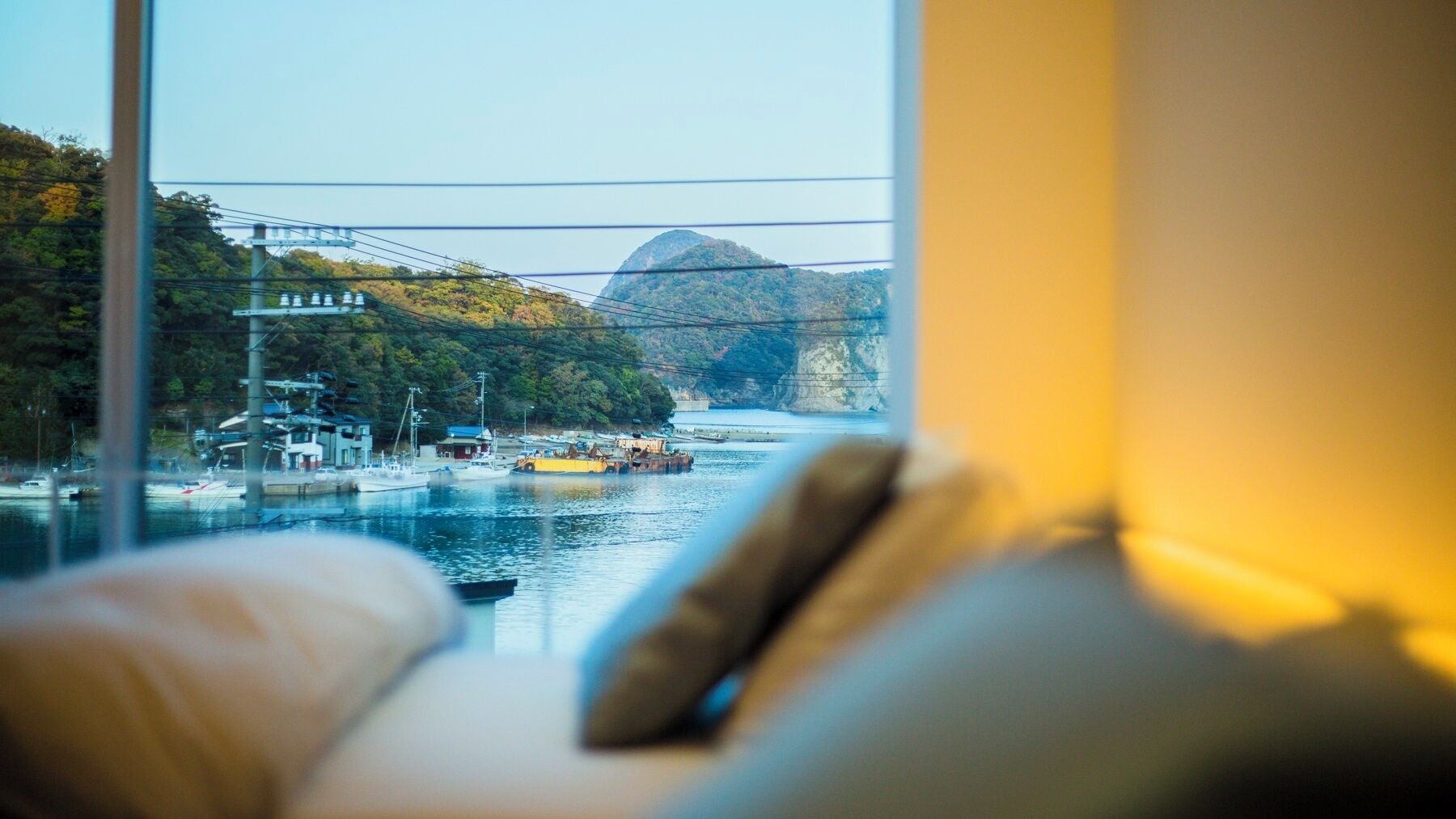 A view from a window with a sofa, a river, boats, and a bridge.