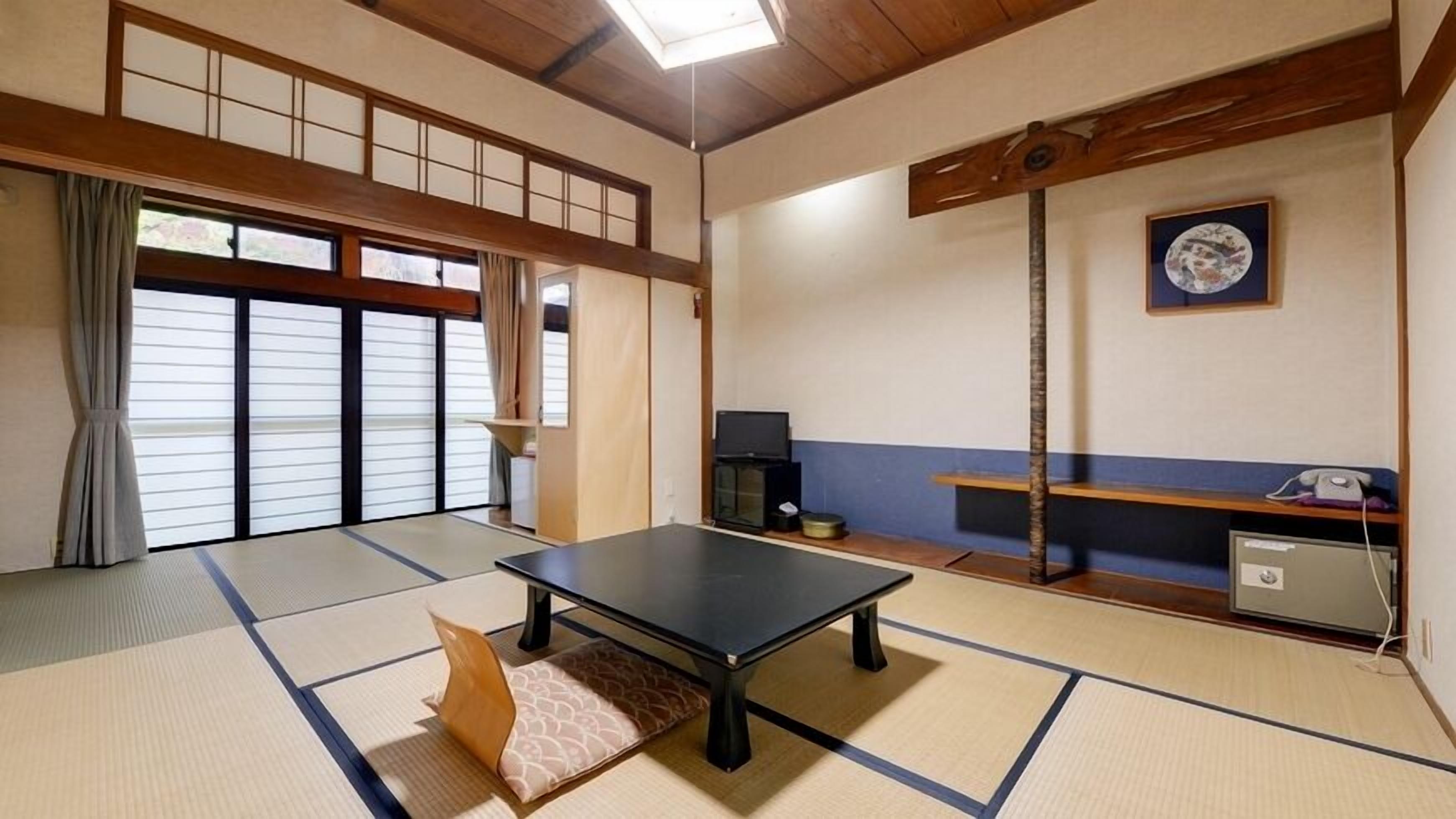A tatami mat room with a tatami mat table, a television, and a cabinet.