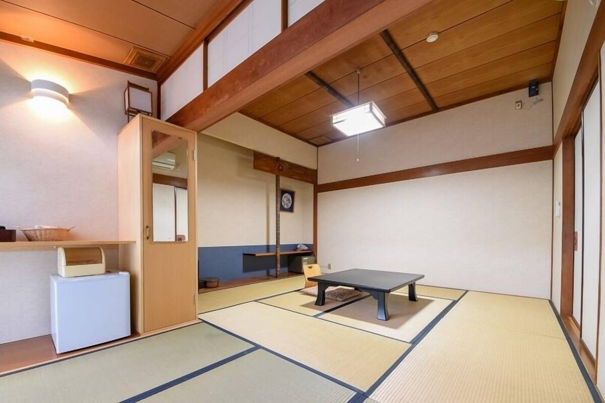 A traditional Japanese room with tatami flooring, a low table, a small cabinet, and a mirror.