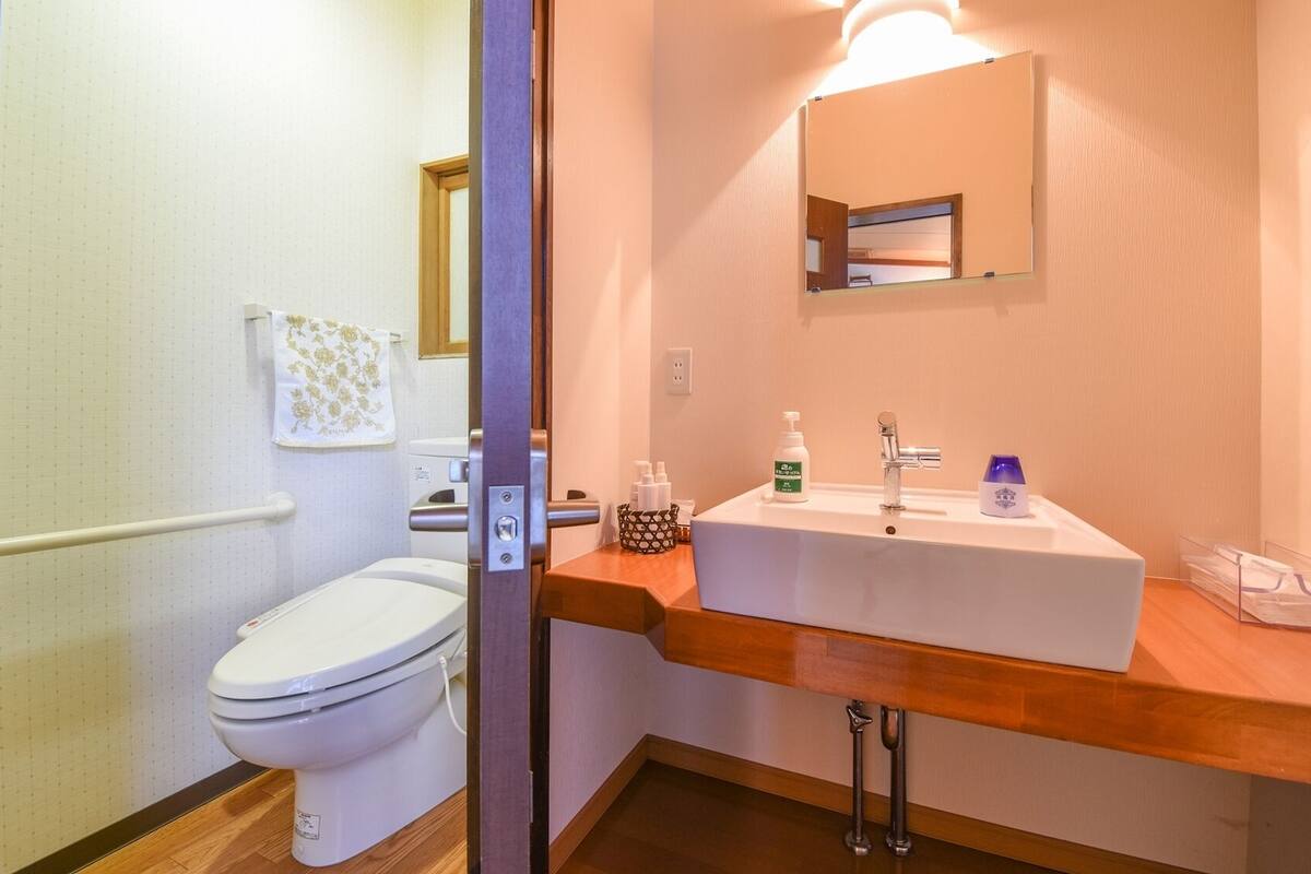 A bathroom with a toilet, sink, and mirror.