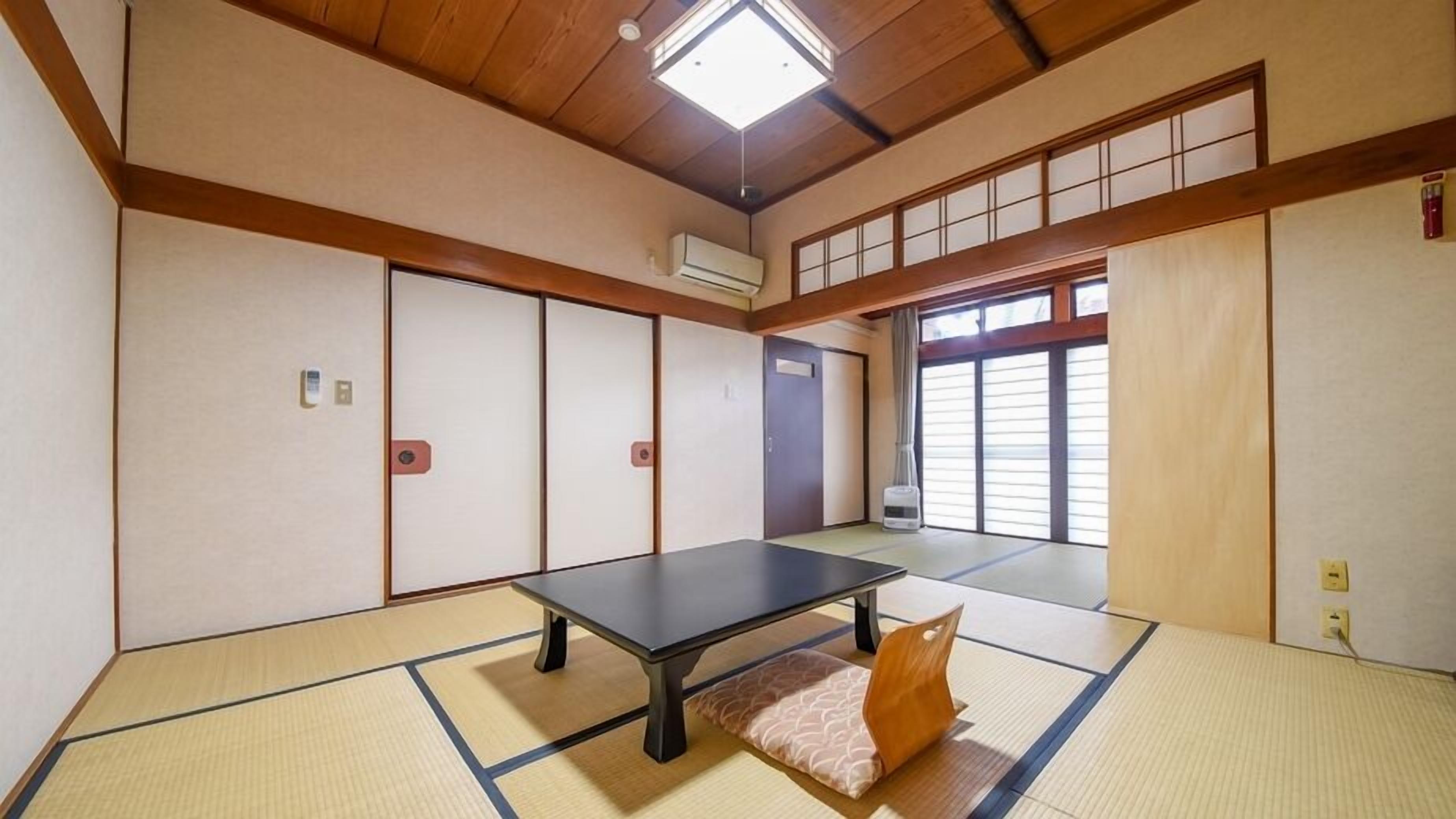 A tatami mat room with a tatami mat table, sliding doors, and a ceiling fan.