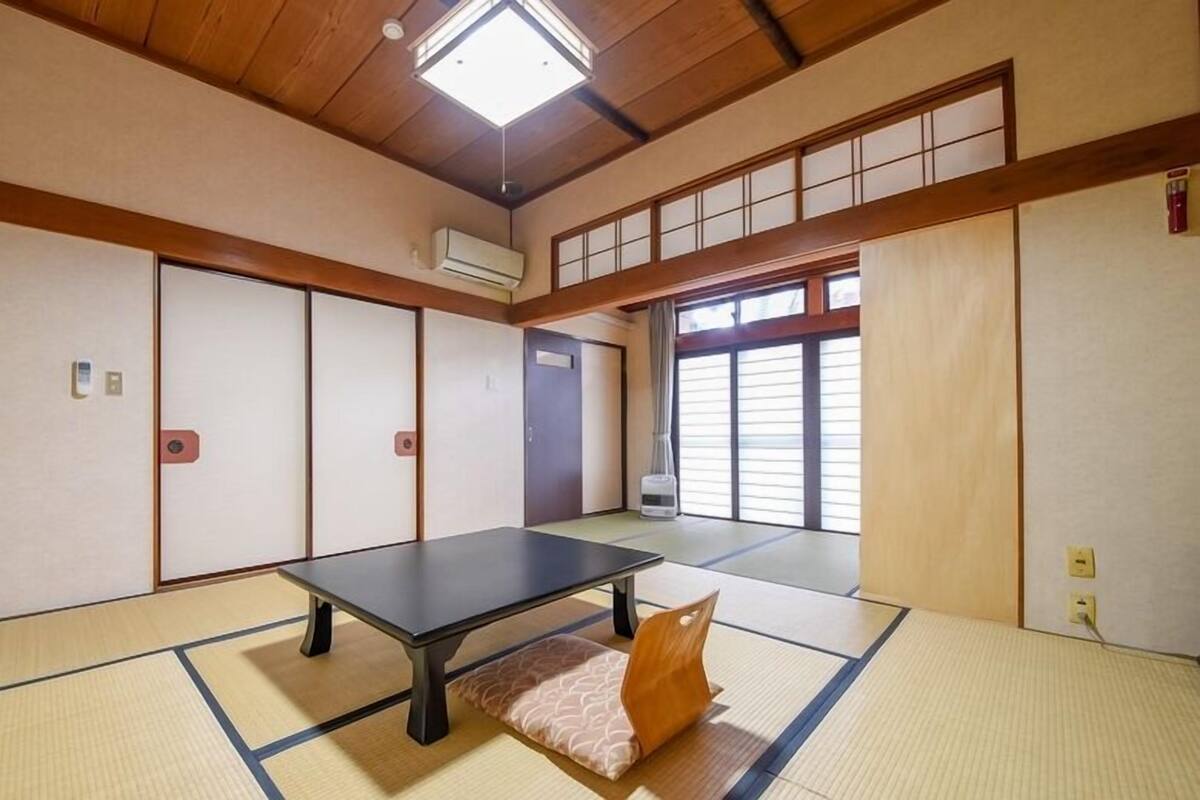 A tatami mat room with a tatami mat table, sliding doors, and a ceiling fan.