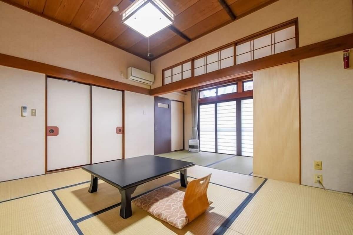 A tatami mat room with a tatami mat table, sliding doors, and a ceiling fan.