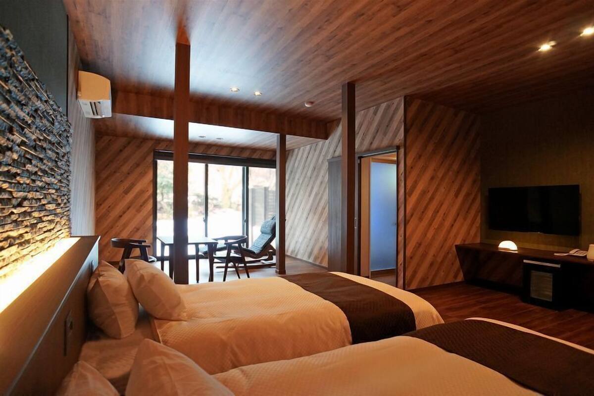 A modern hotel room with a large bed, a desk, a chair, and a TV.