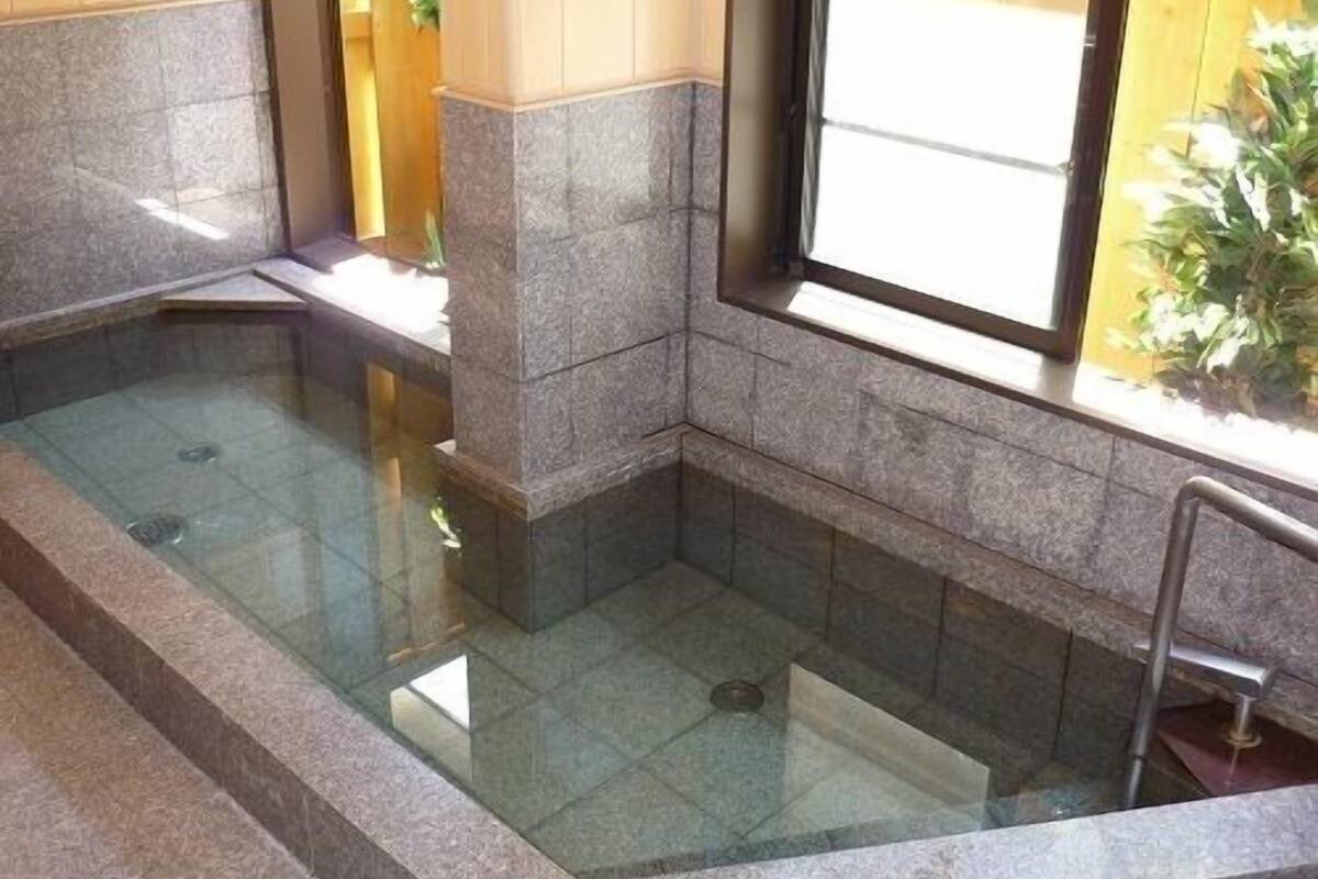 Un jacuzzi con revestimiento de piedra, piso de vidrio, paredes de madera y ventana con vistas.