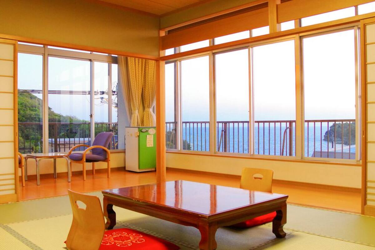 Una habitación tradicional japonesa con suelo de tatami, una mesa baja y sillas.