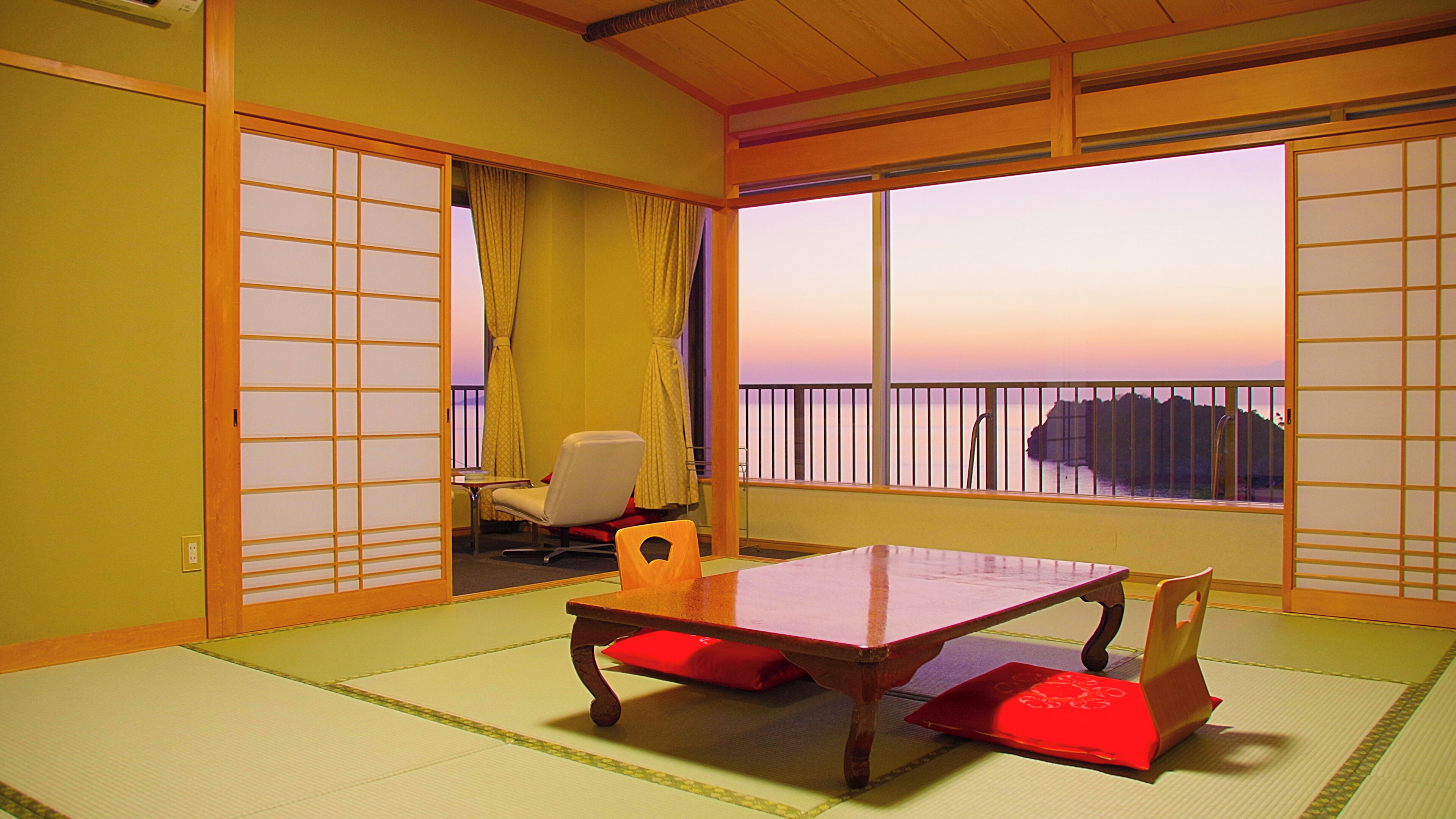 Een traditionele Japanse kamer met tatami vloerbedekking, een lage tafel en uitzicht op zee.