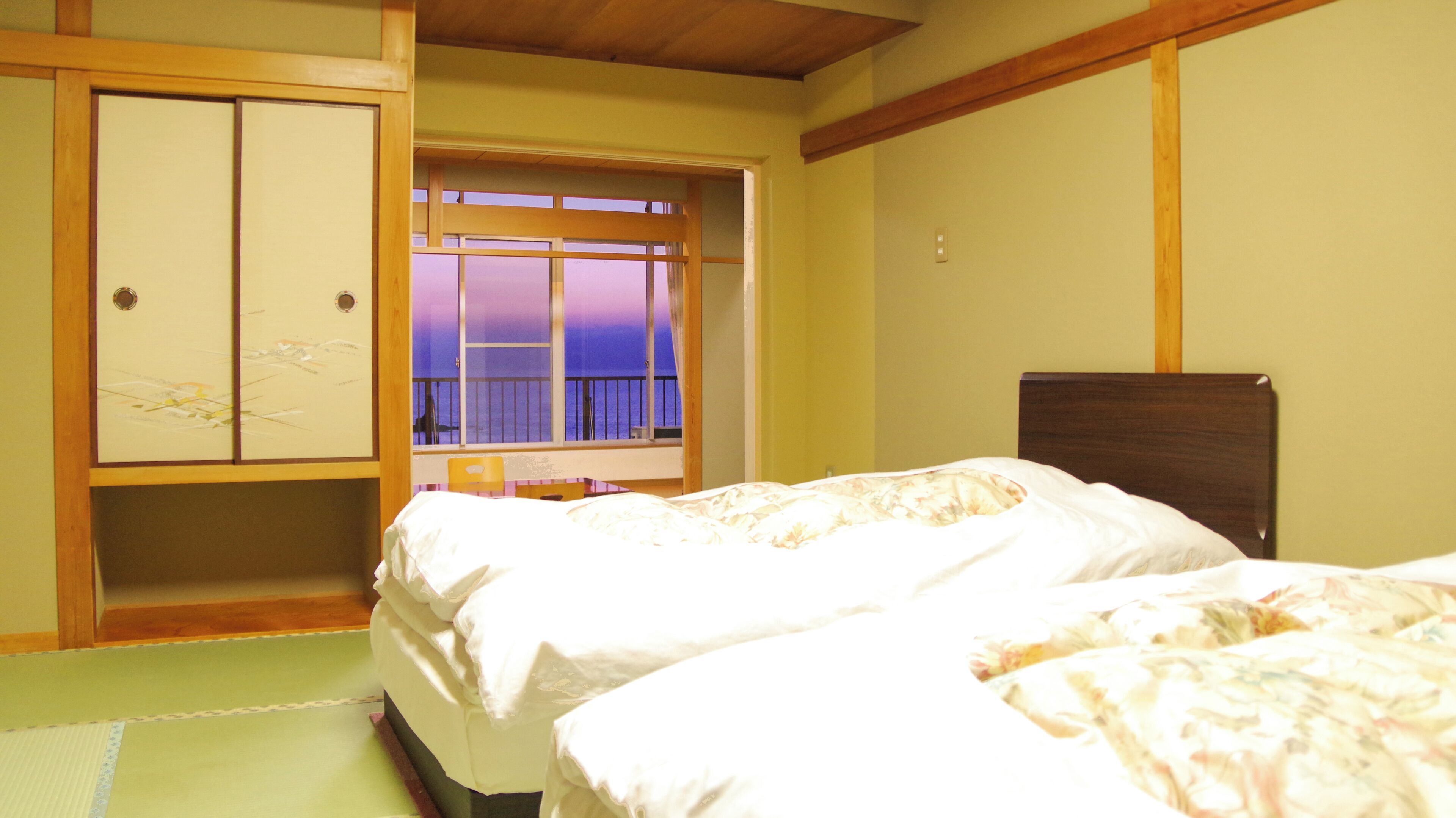 Een hotelkamer met twee bedden, een houten garderobe, een raam met uitzicht en een houten plafond.