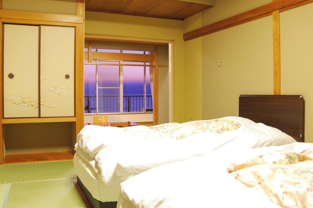 Una habitación de hotel con dos camas, un armario de madera, una ventana con vistas y un techo de madera.