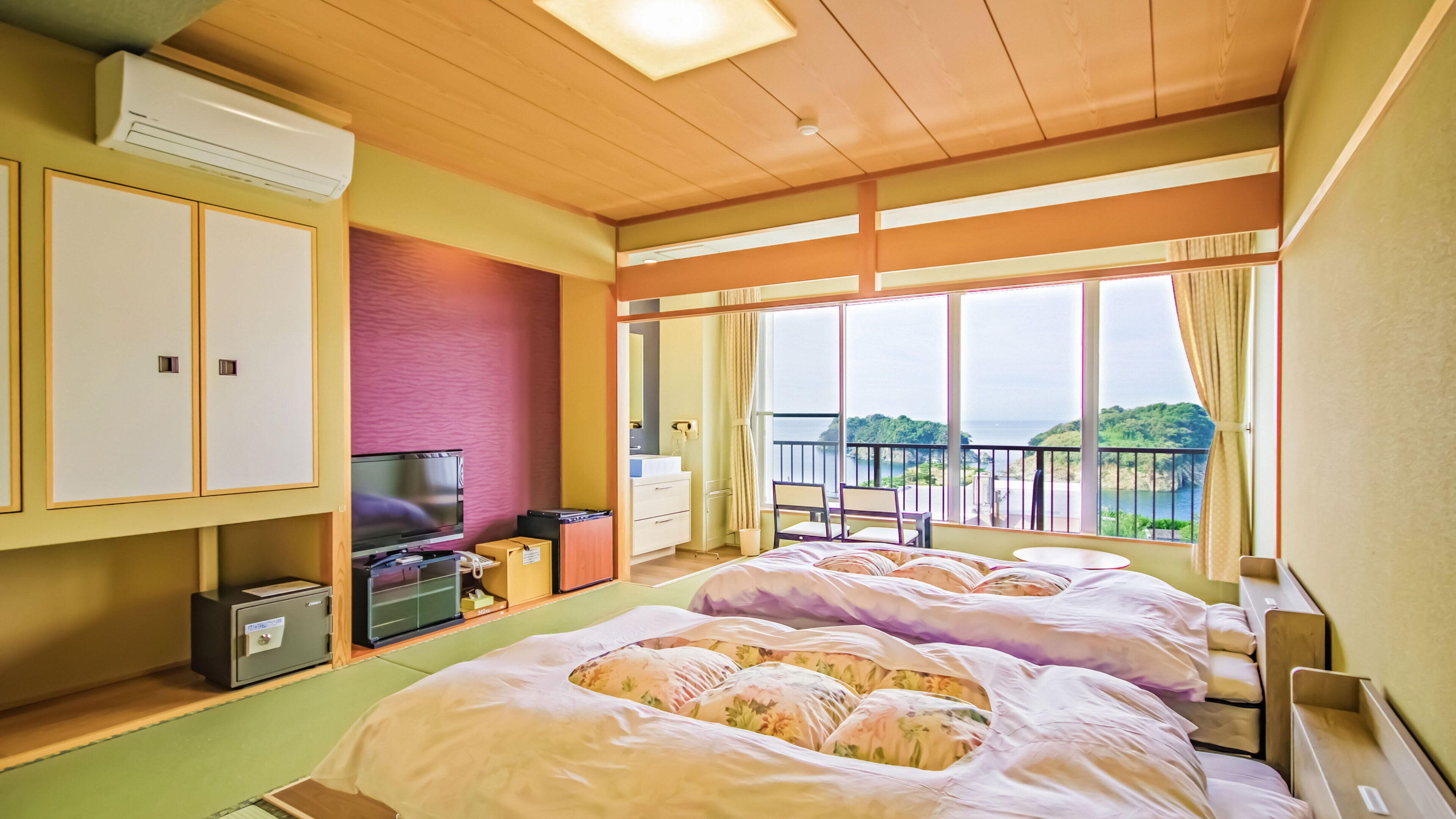 Een hotelkamer met twee bedden, een televisie, een bureau en een balkon met uitzicht.