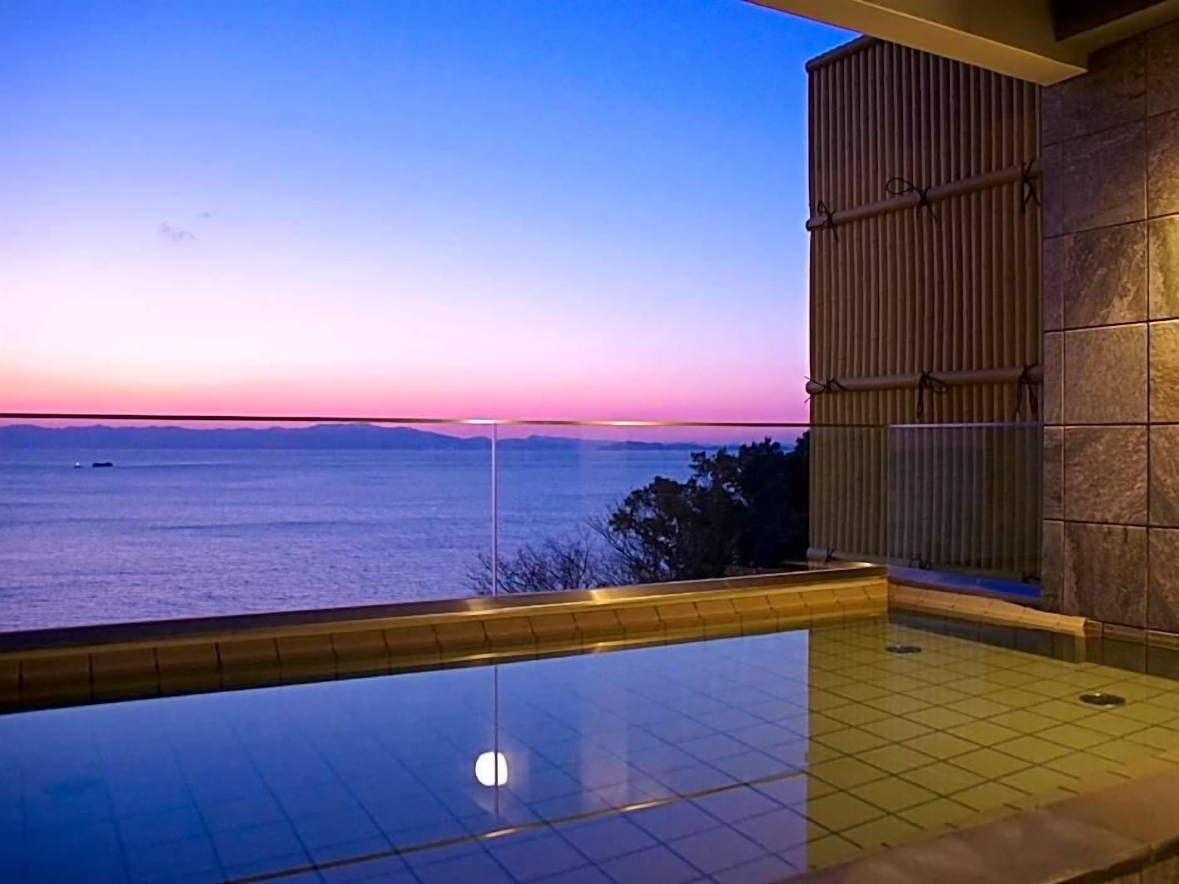 En pool med udsigt til havet i skumringen.