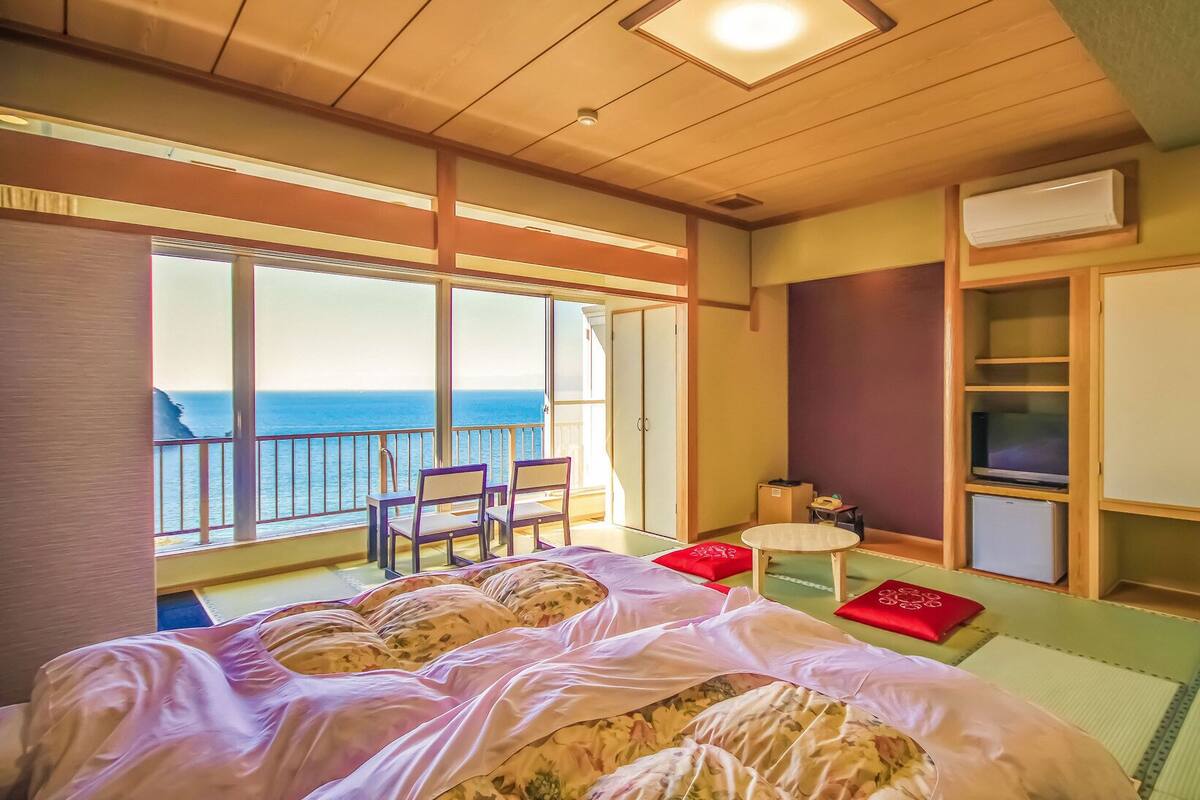 Una habitación con cama, una mesita, televisión y armario. Tiene un balcón con vistas al mar.