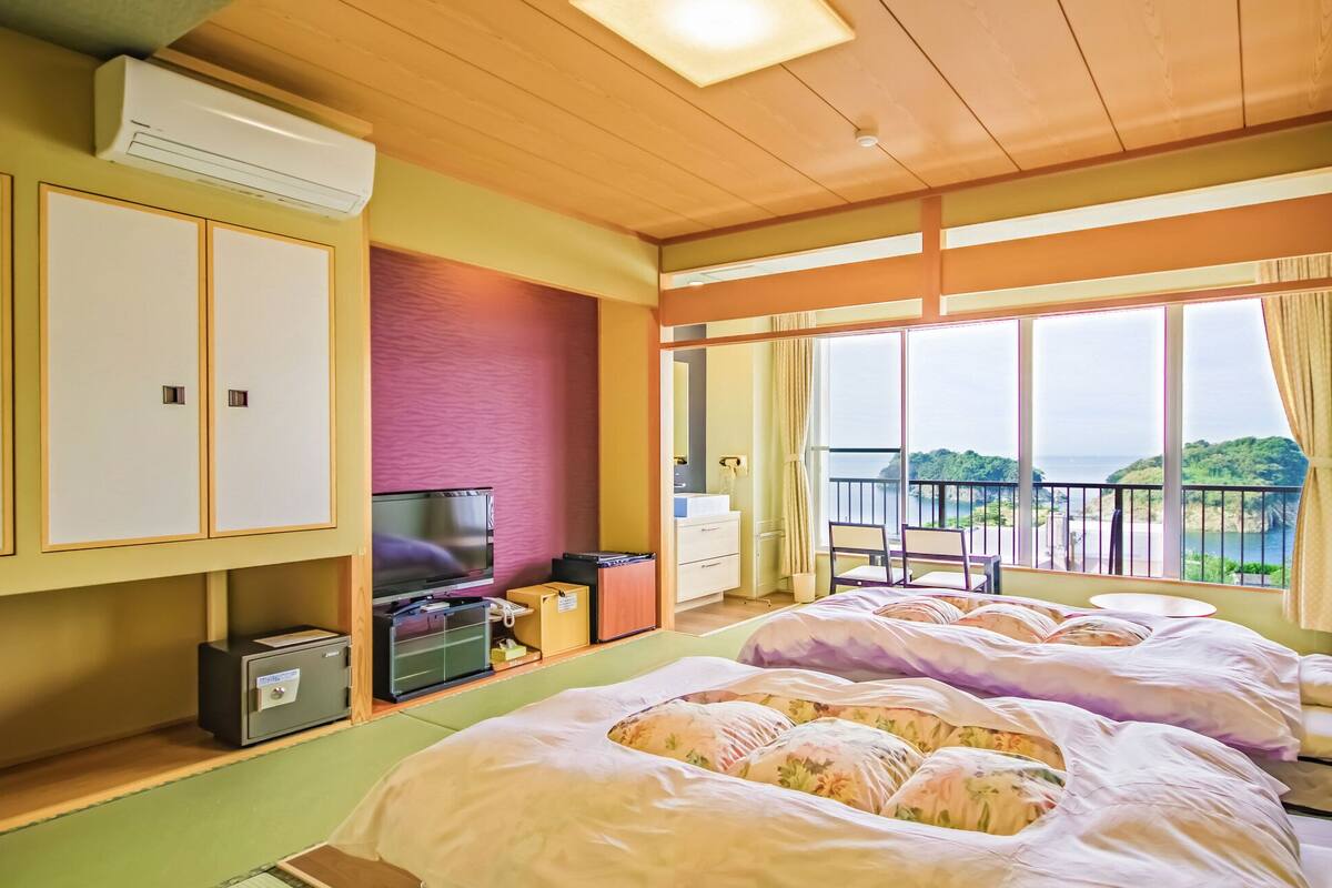 Habitación de hotel con dos camas, televisión, minibar y balcón con vistas.