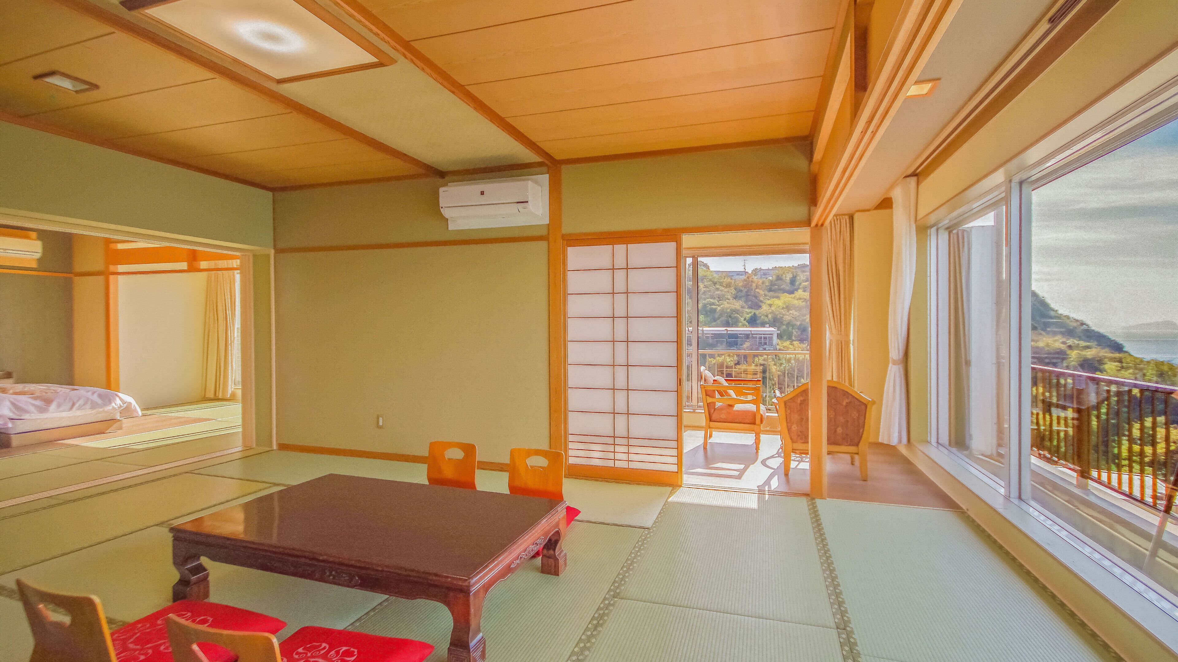 Een traditionele Japanse kamer met tatami vloerbedekking, een lage tafel en schuifdeuren naar een balkon met uitzicht.