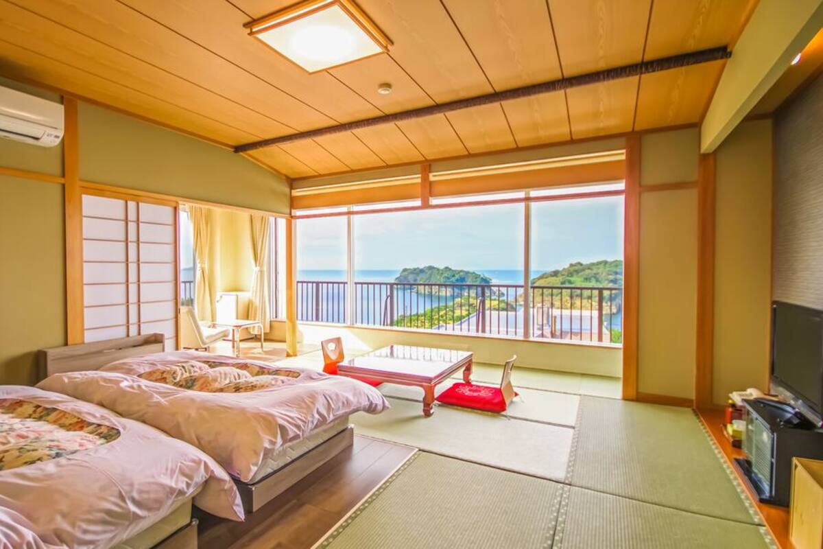 Habitación con dos camas, televisión y vista al mar.